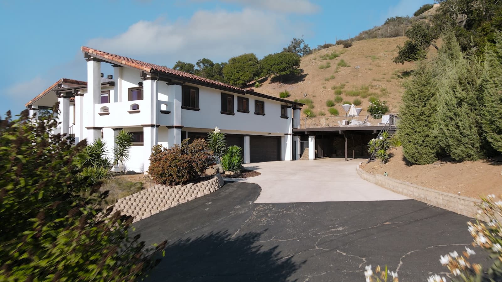 Long asphalt driveway leading to a large white home