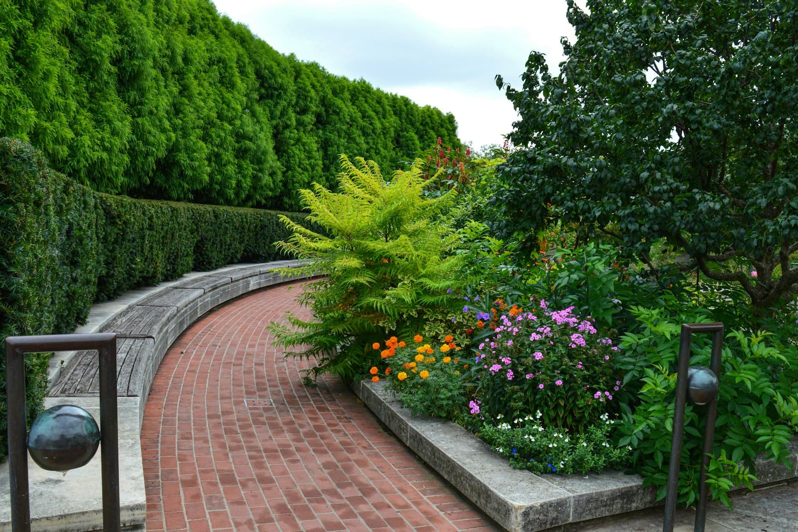 Manicured garden beds with flowers along a brick walkway