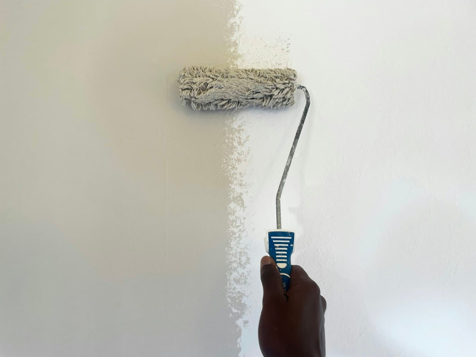 Painter applying fresh paint to a wall with a roller