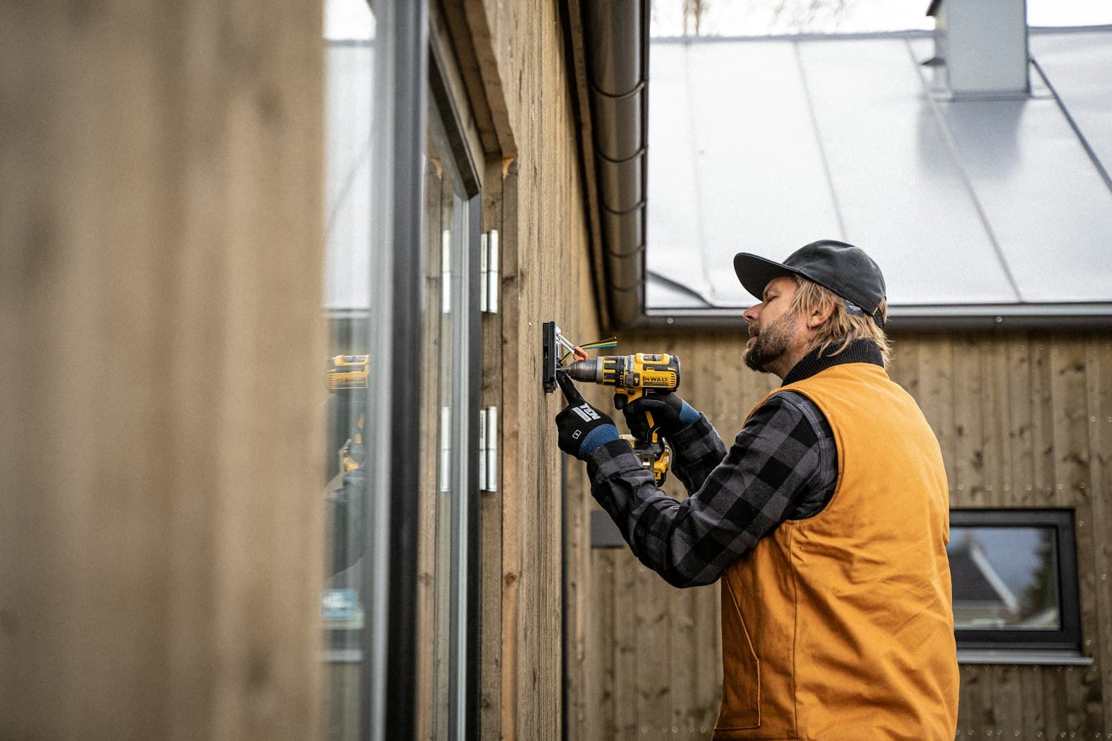 Contractor with a drill repairing wood siding on a home exterior